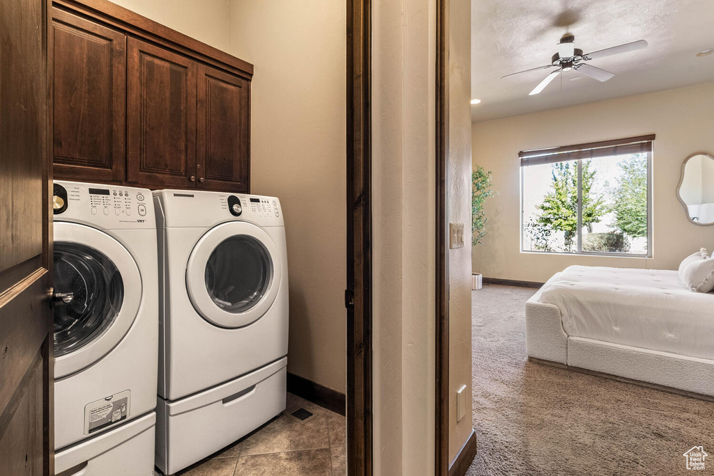 Washroom featuring cabinet space, washing machine and dryer, a ceiling fan, and light carpet