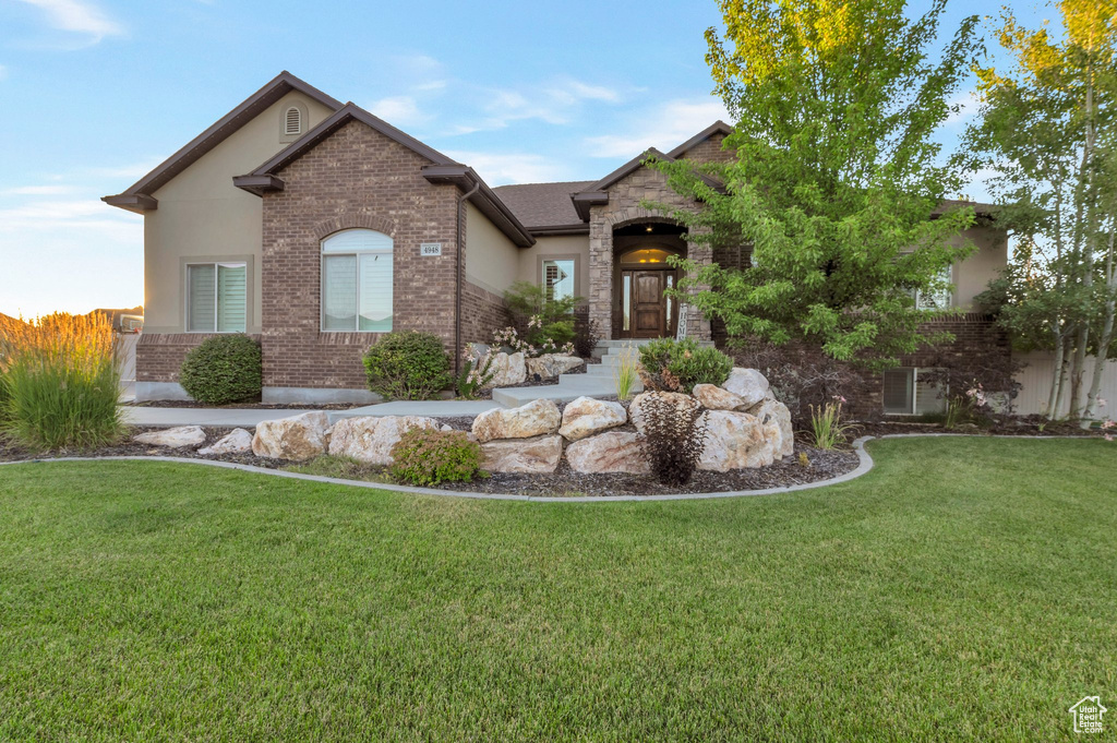 View of front facade with a front yard, stucco siding, brick siding, and stone siding