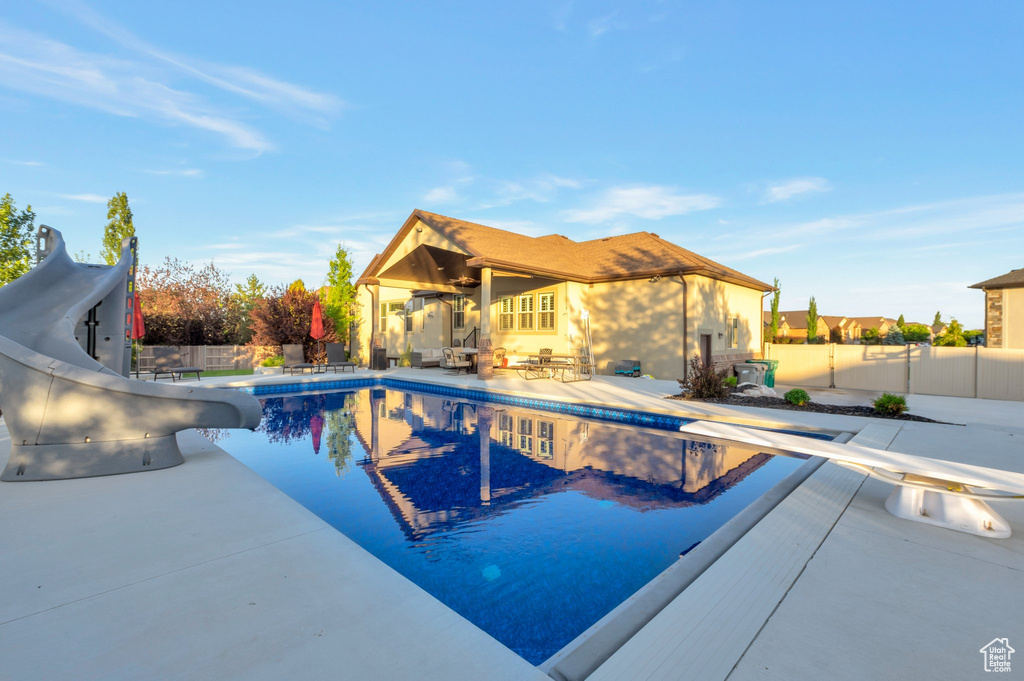 View of swimming pool featuring a water slide, a fenced backyard, a patio area, and a diving board