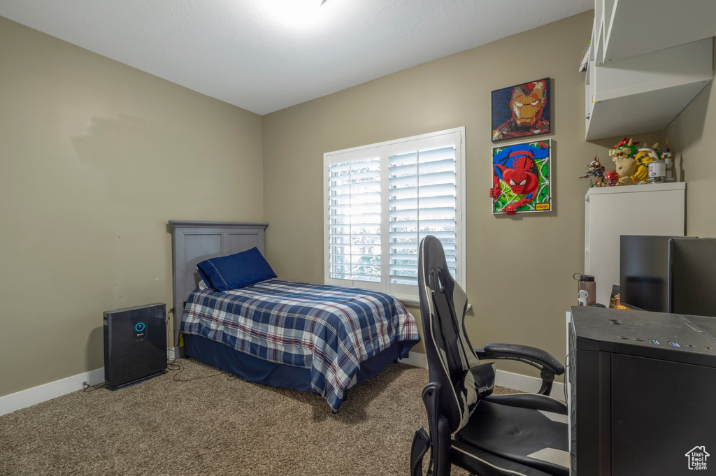 Carpeted bedroom with baseboards and an office area