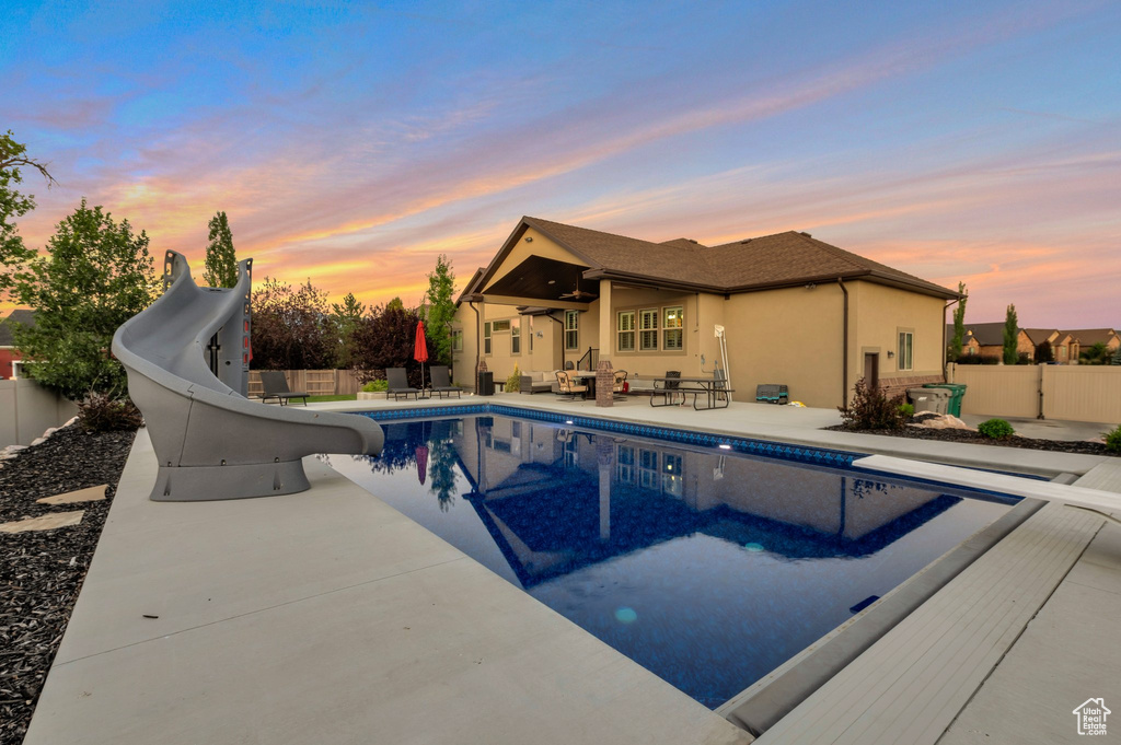 View of pool featuring a water slide, a patio area, and a diving board
