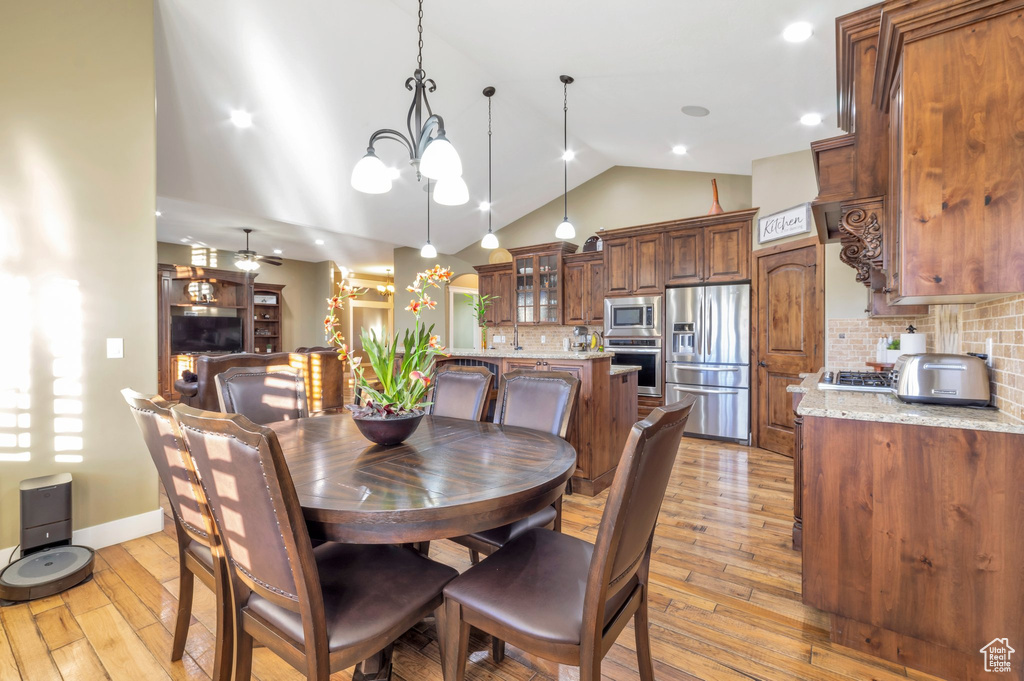 Dining space featuring vaulted ceiling, light wood-style floors, and a chandelier