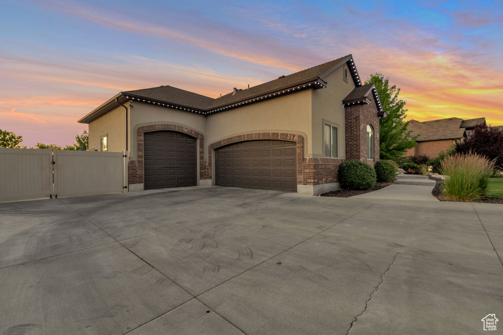 Mediterranean / spanish house featuring an attached garage, concrete driveway, stucco siding, and a gate