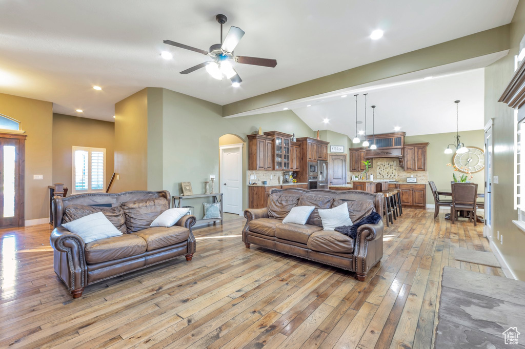 Living area featuring light wood finished floors, ceiling fan, arched walkways, lofted ceiling, and recessed lighting