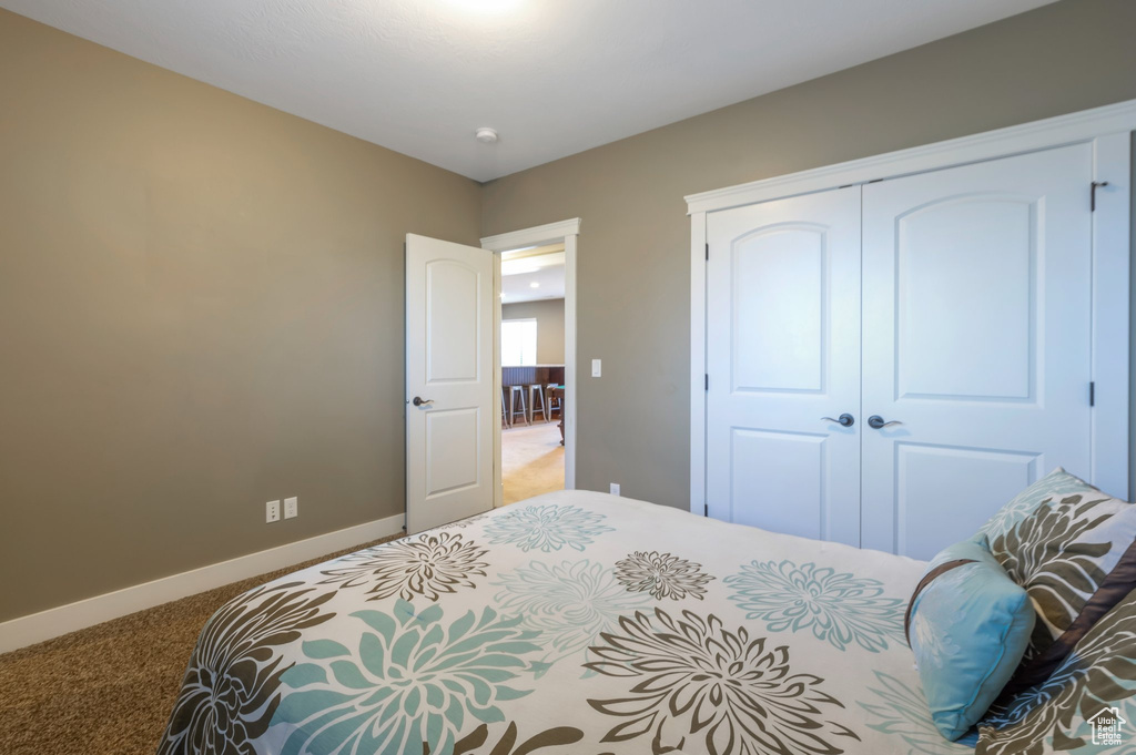 Carpeted bedroom with a closet and baseboards