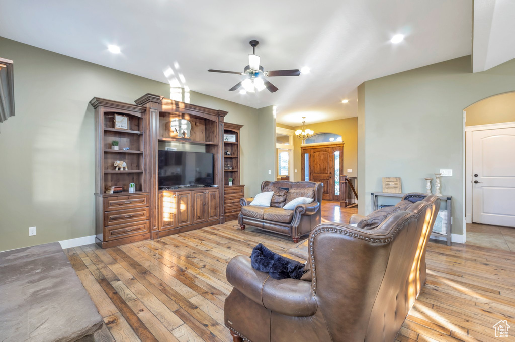 Living room featuring light wood-type flooring, a ceiling fan, a chandelier, recessed lighting, and arched walkways