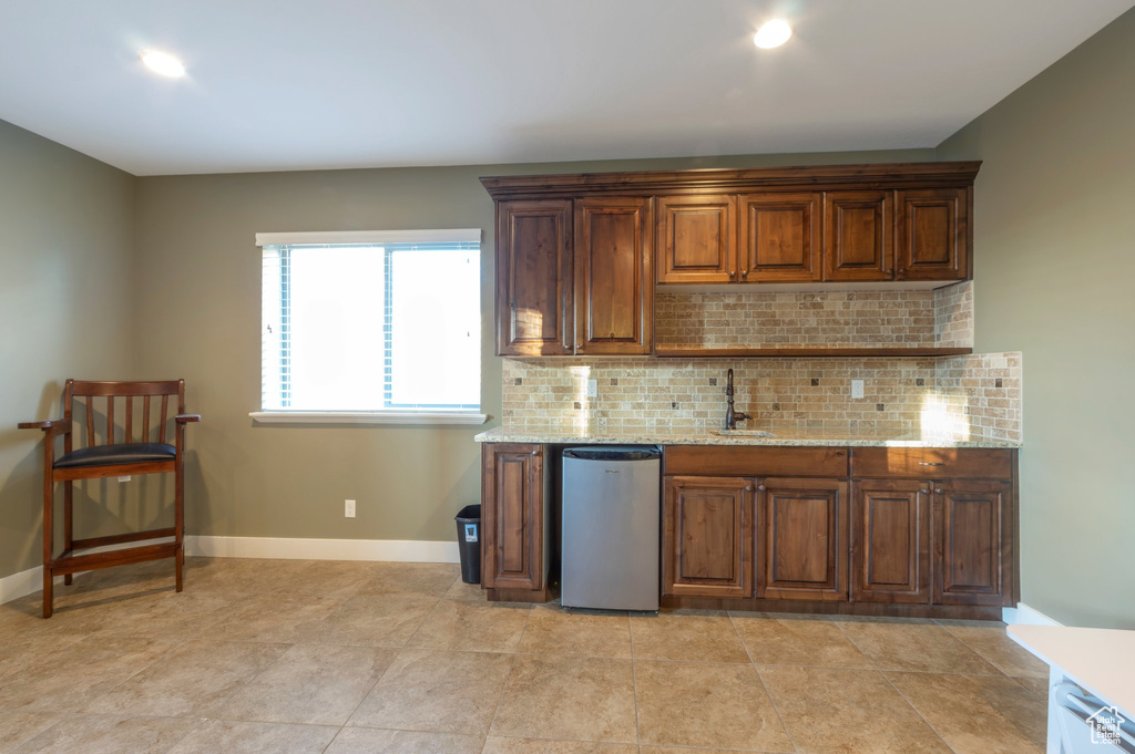 Kitchen featuring dishwasher, tasteful backsplash, and light stone counters