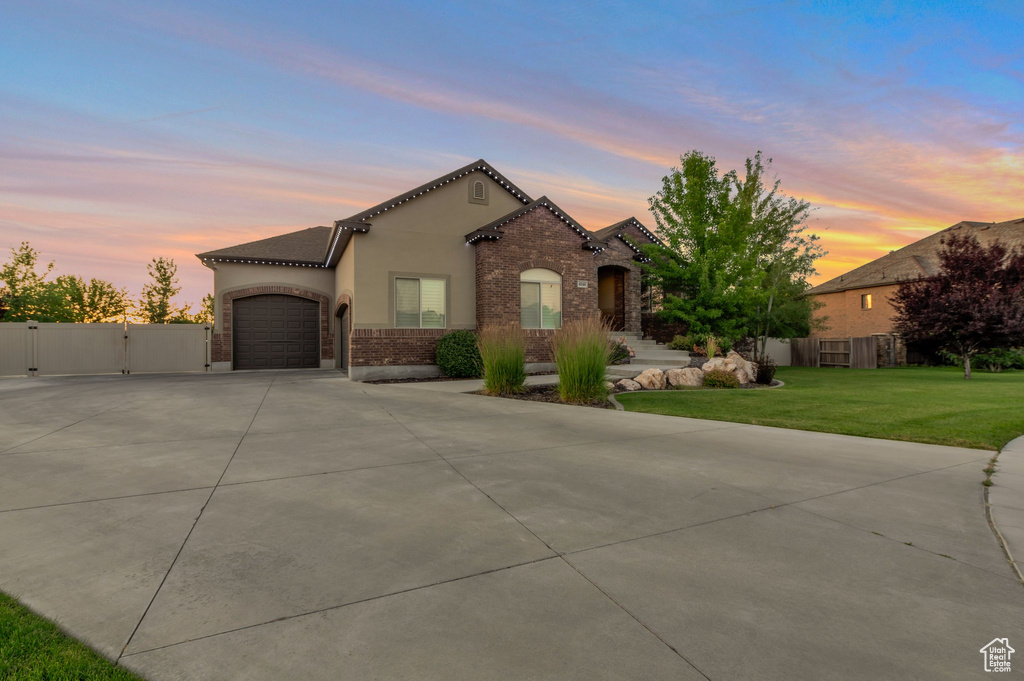 Mediterranean / spanish house featuring concrete driveway, a garage, a gate, stucco siding, and brick siding