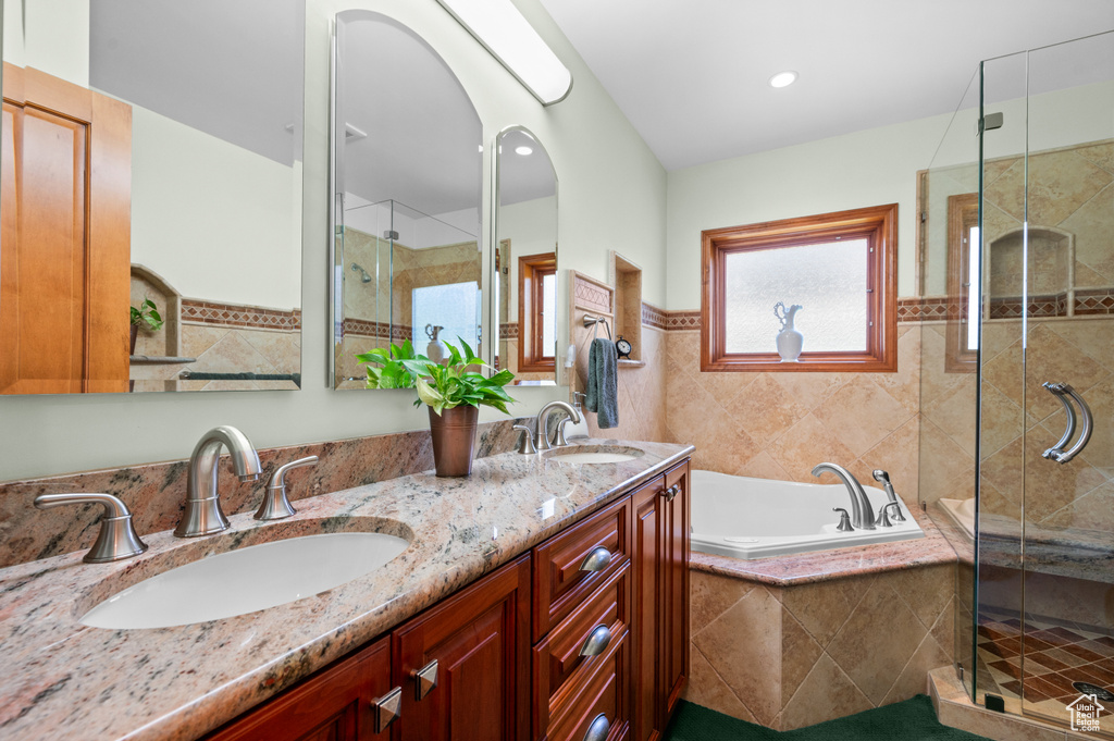 Bathroom featuring a stall shower, a bath, and double vanity