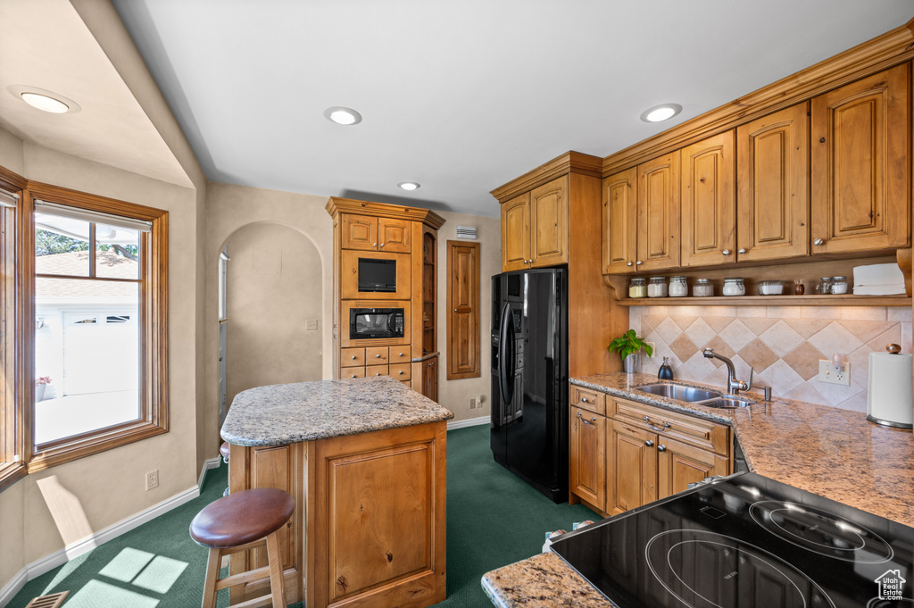 Kitchen with black appliances, dark carpet, a kitchen island, open shelves, and backsplash