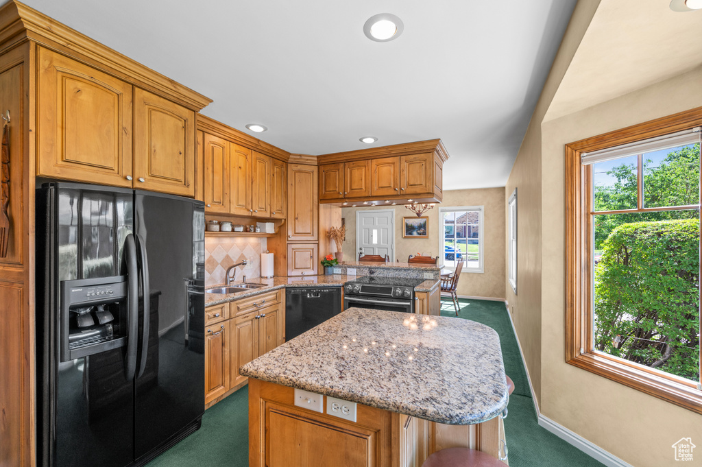 Kitchen featuring black appliances, dark colored carpet, healthy amount of natural light, a center island, and recessed lighting