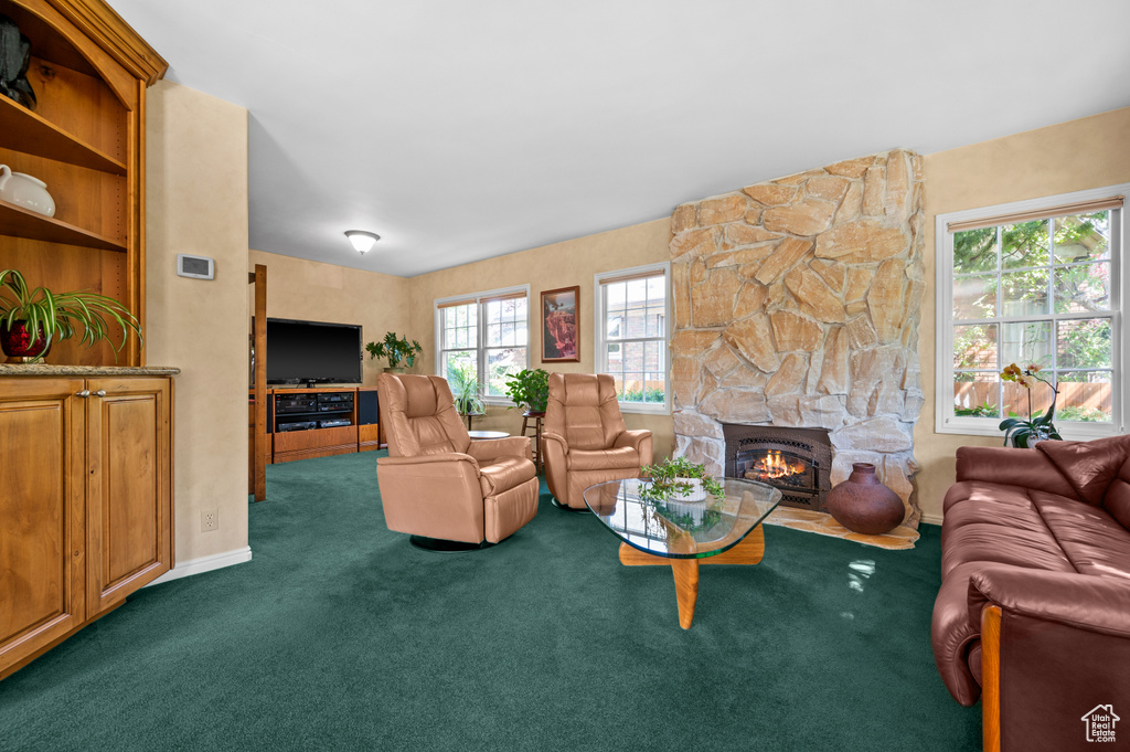 Carpeted living room with a stone fireplace and baseboards