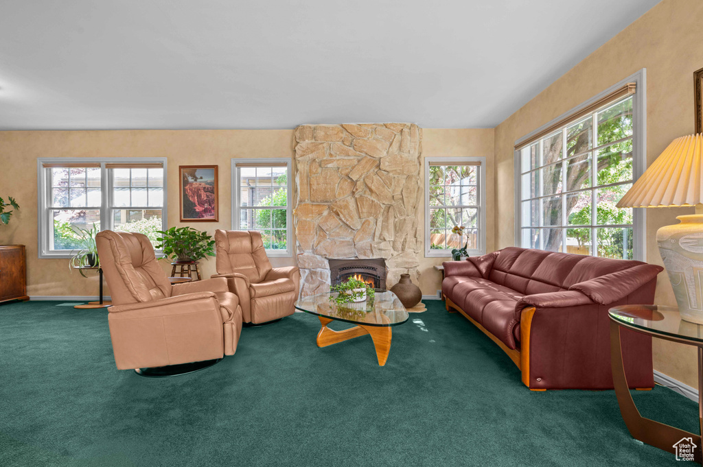 Living area featuring carpet floors, healthy amount of natural light, and a stone fireplace