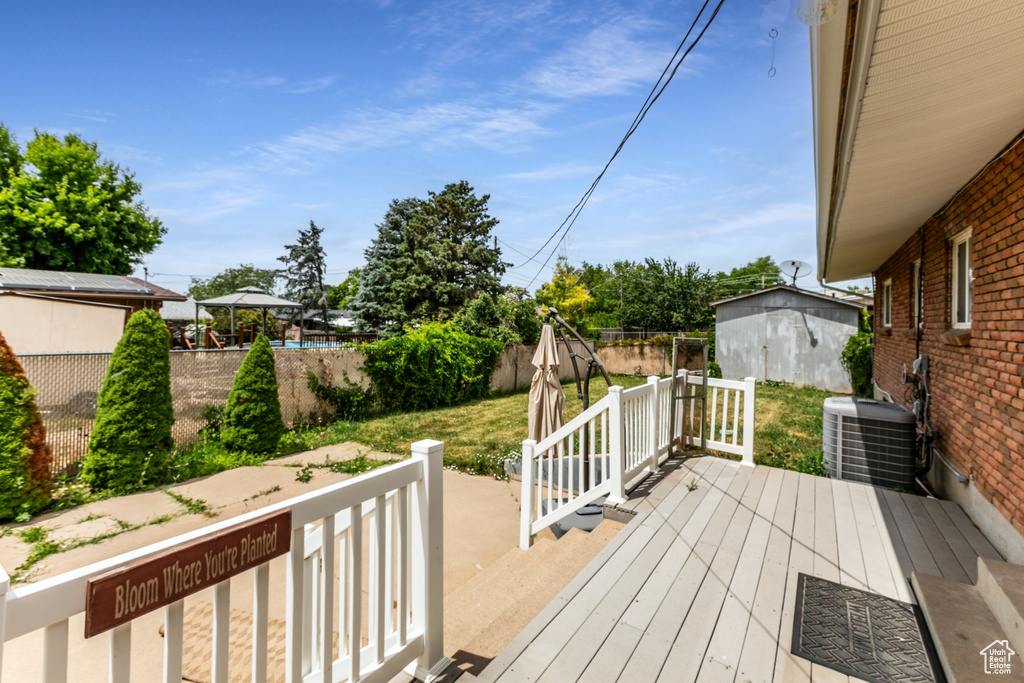 Wooden terrace featuring a fenced backyard, an outbuilding, and a patio