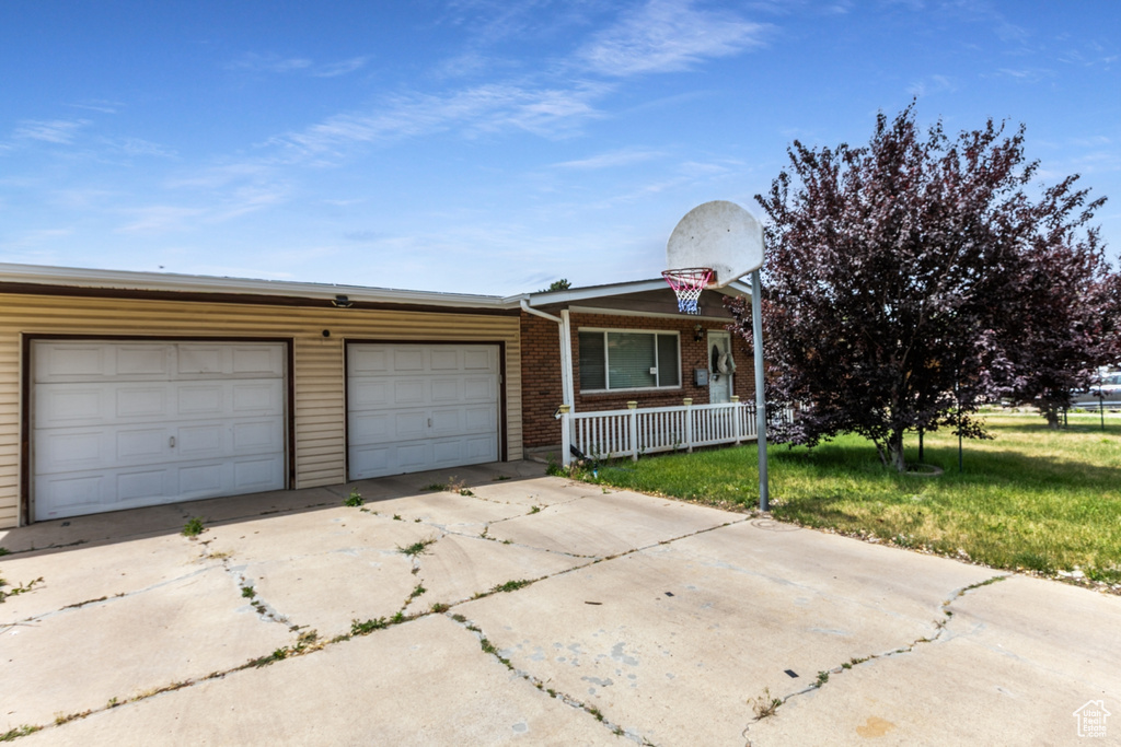 View of front of property featuring a porch, driveway, an attached garage, a front yard, and brick siding