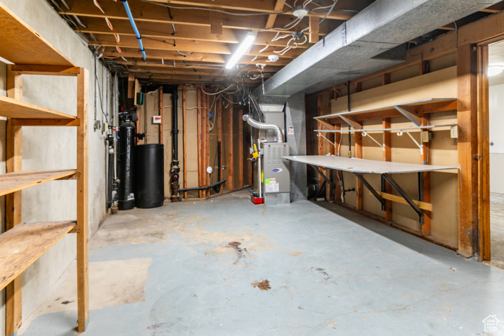 Unfinished below grade area featuring heating unit and a water softener