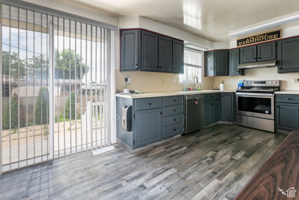 Kitchen featuring stainless steel appliances, under cabinet range hood, dark wood-style floors, light countertops, and gray cabinets
