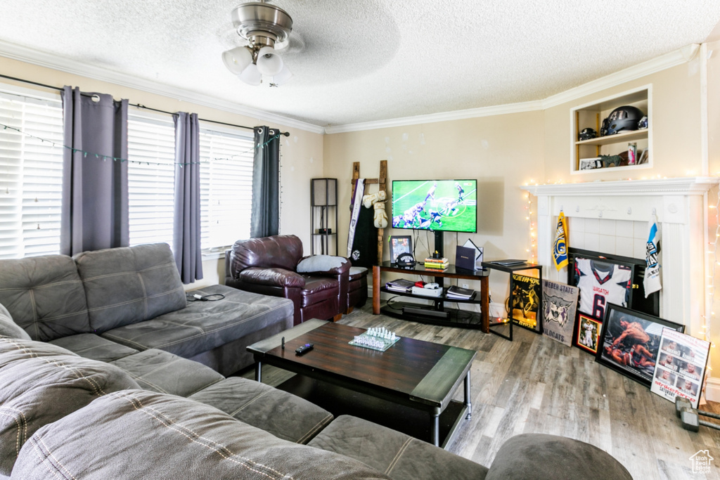Living room featuring wood finished floors, crown molding, ceiling fan, and a textured ceiling