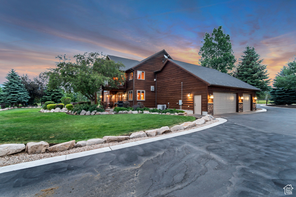 View of home\'s exterior featuring a lawn, a balcony, a garage, stone siding, and driveway