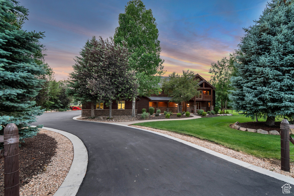 View of front of house featuring a lawn, driveway, and stone siding