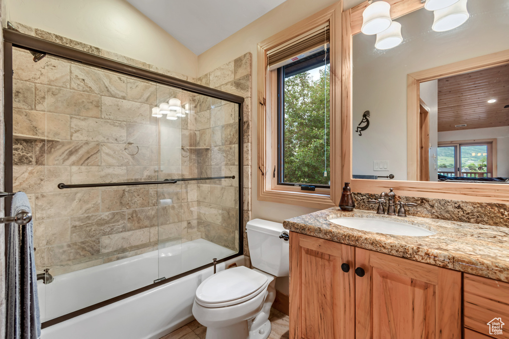 Full bath featuring plenty of natural light, vanity, combined bath / shower with glass door, and vaulted ceiling