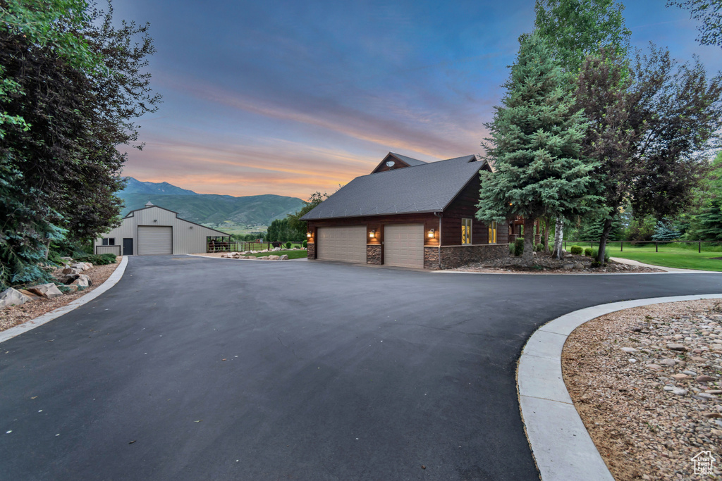 Property exterior at dusk with a mountain view, stone siding, and a garage