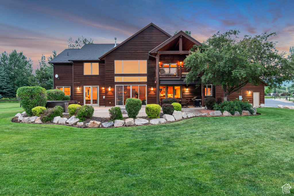 Back of house at dusk featuring a yard, a patio area, and an attached garage
