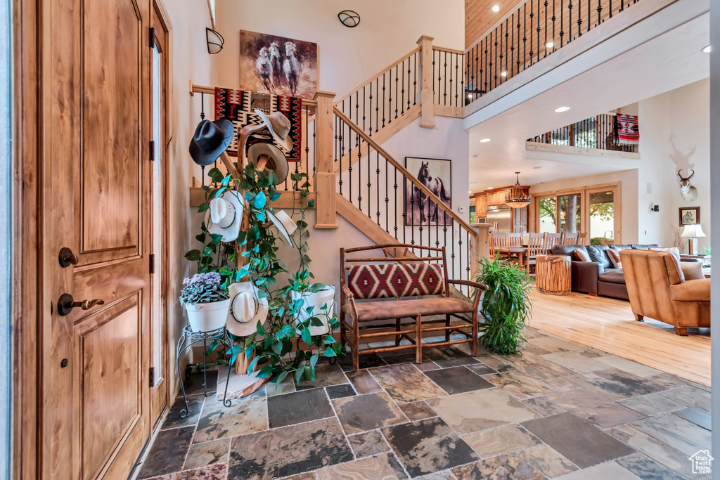 Stairway featuring a high ceiling, stone tile flooring, and recessed lighting