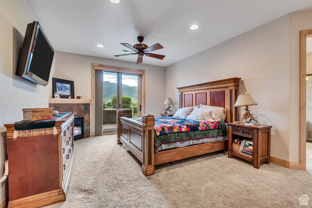 Bedroom featuring access to outside, light colored carpet, a tiled fireplace, recessed lighting, and a ceiling fan