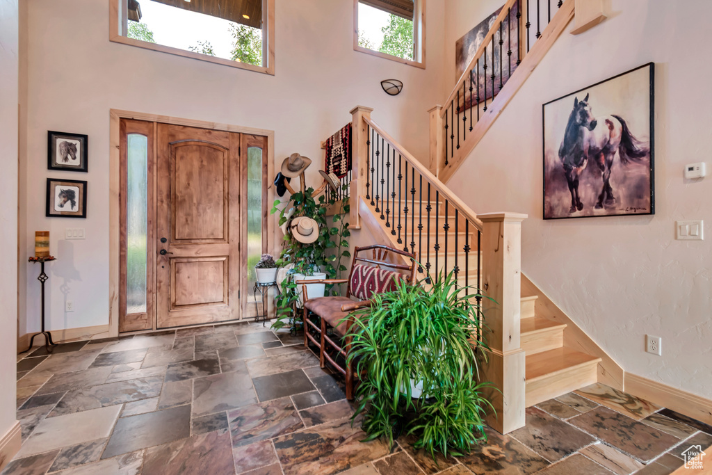 Entryway with a high ceiling, stairs, and stone tile flooring