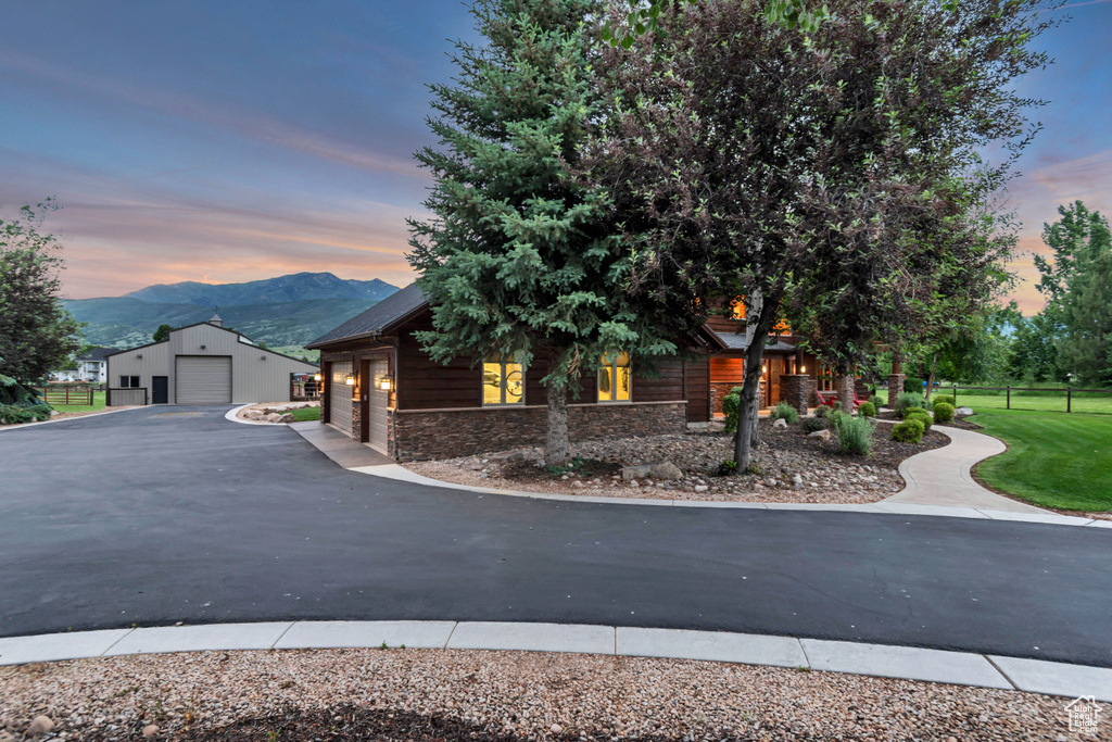 View of front of property with stone siding, a mountain view, an outbuilding, and a garage