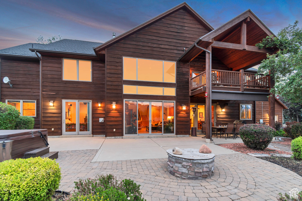 Rear view of house with a hot tub, an outdoor fire pit, and a patio area