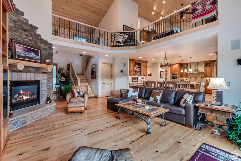 Living room with a high ceiling, stairs, wood finished floors, a fireplace, and wooden ceiling