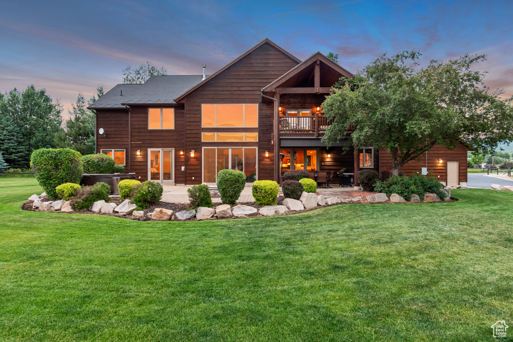 Back of house at dusk with a patio and a yard
