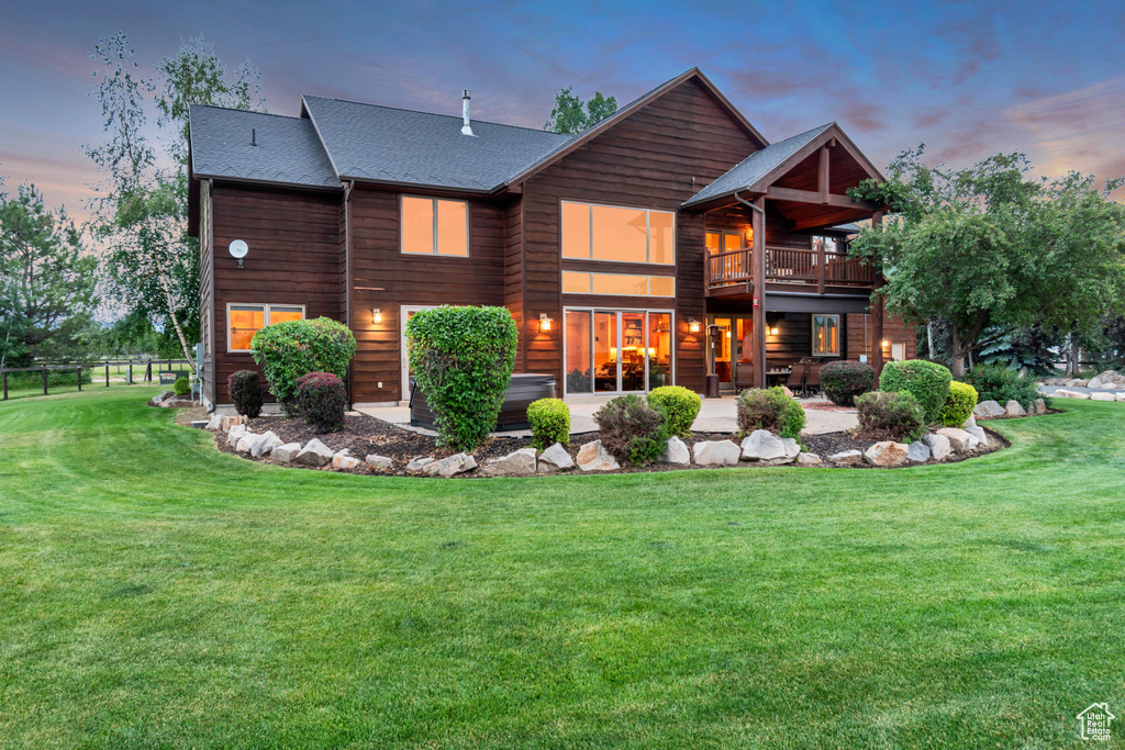 Back of house at dusk featuring a patio area, roof with shingles, and a deck