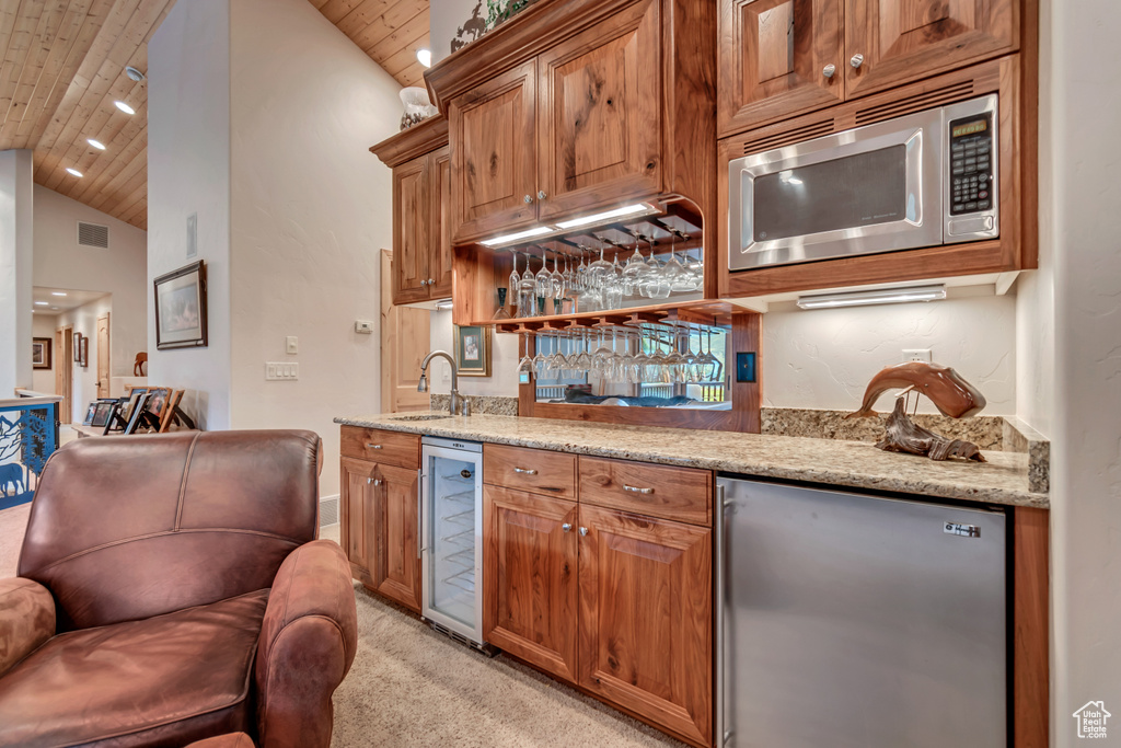 Indoor wet bar with stainless steel appliances, wine cooler, wood ceiling, light carpet, and vaulted ceiling
