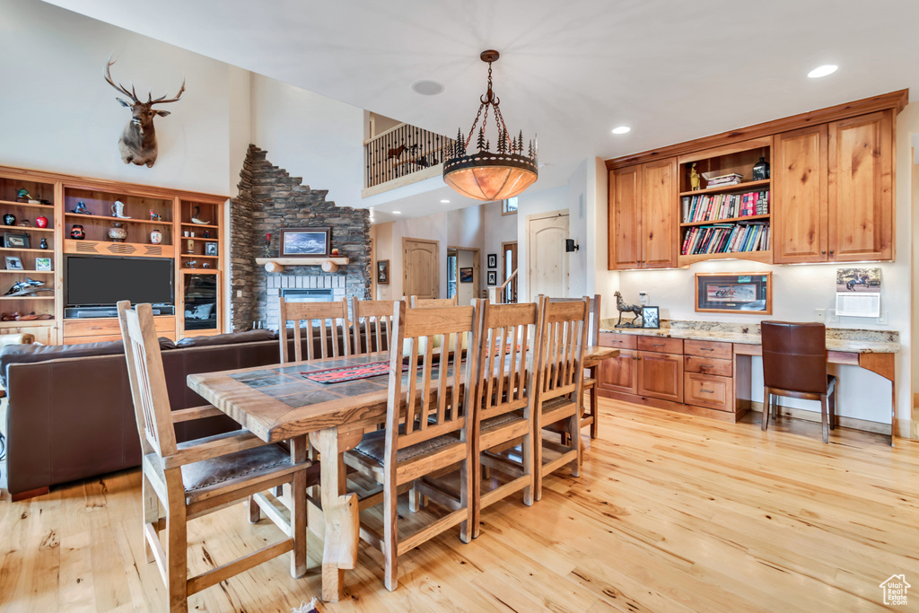 Dining area featuring built in desk, light wood finished floors, recessed lighting, and a stone fireplace