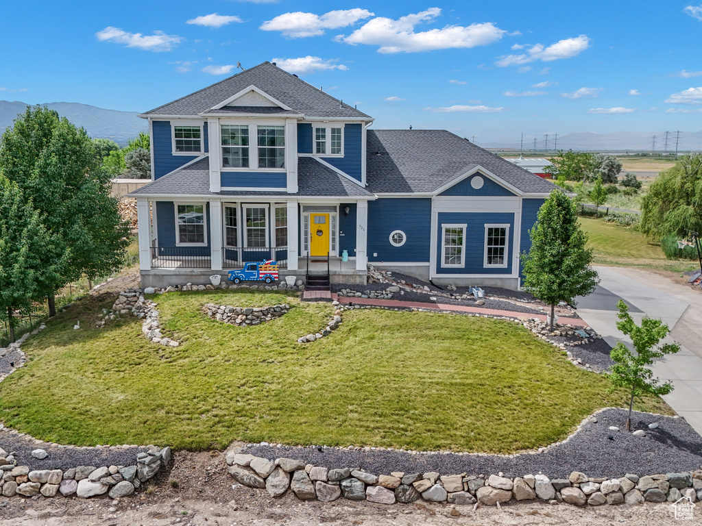 Traditional-style home with a mountain view, a front yard, concrete driveway, and covered porch