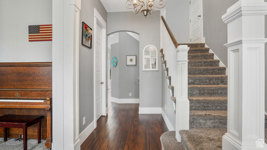 Foyer entrance with arched walkways, wood finished floors, stairway, and a chandelier