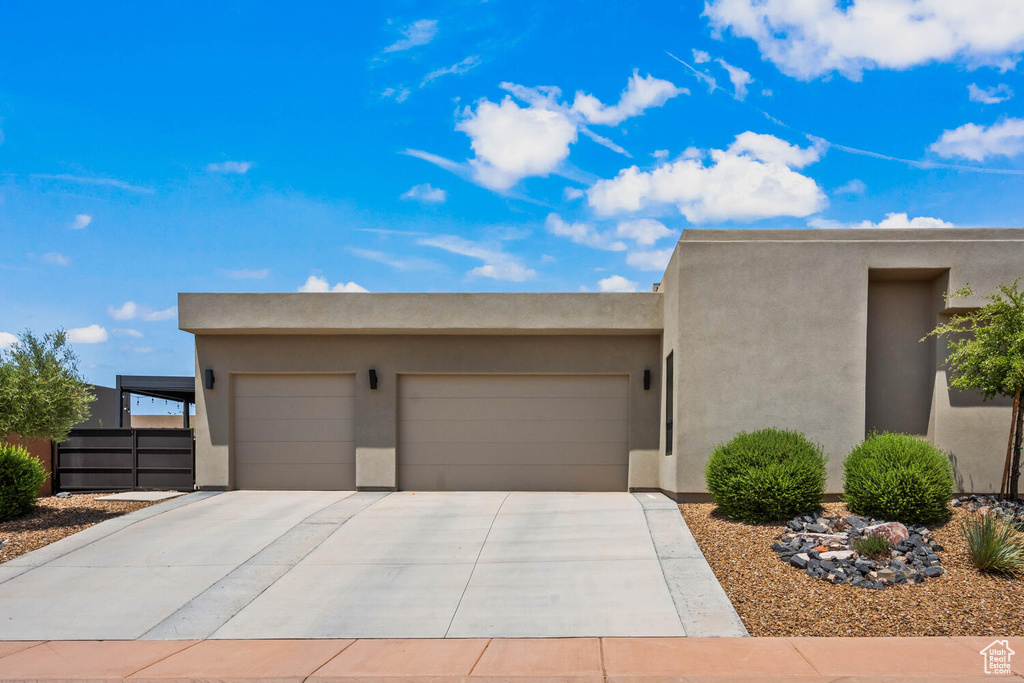 Pueblo-style house featuring an attached garage, concrete driveway, and stucco siding