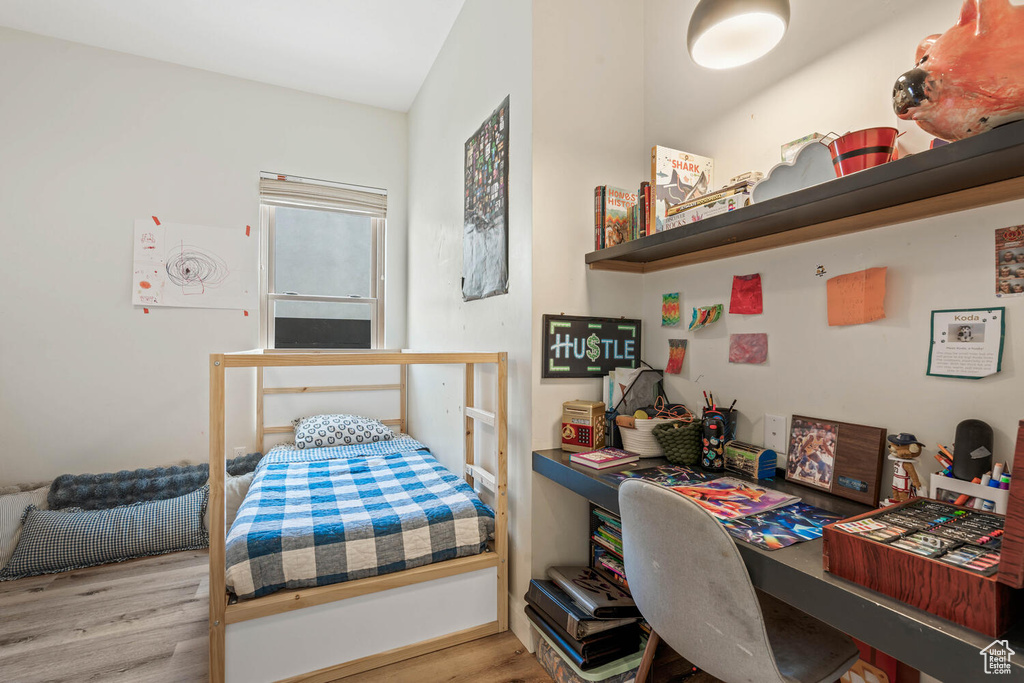 Bedroom with wood finished floors and a desk