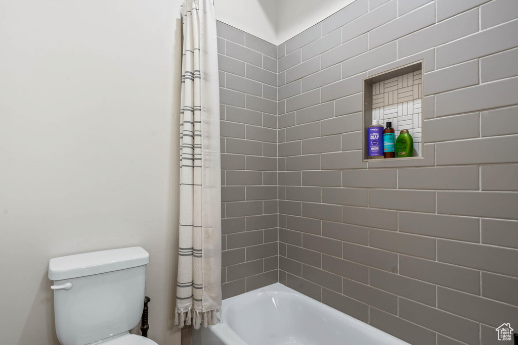 Full bathroom with toilet and shower / bath combo with shower curtain