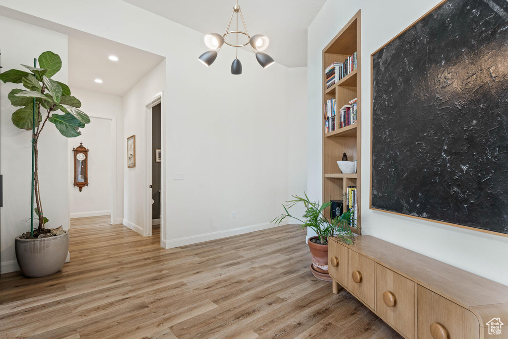 Living area featuring a chandelier, light wood-style flooring, built in shelves, and recessed lighting