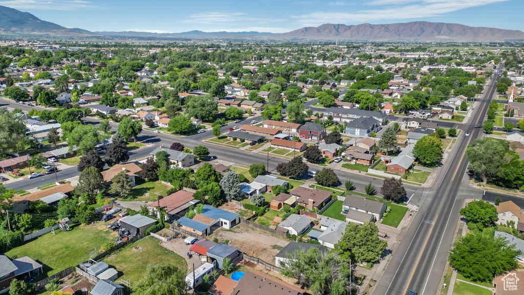 Aerial view of property and surrounding area featuring mountains and nearby suburban area