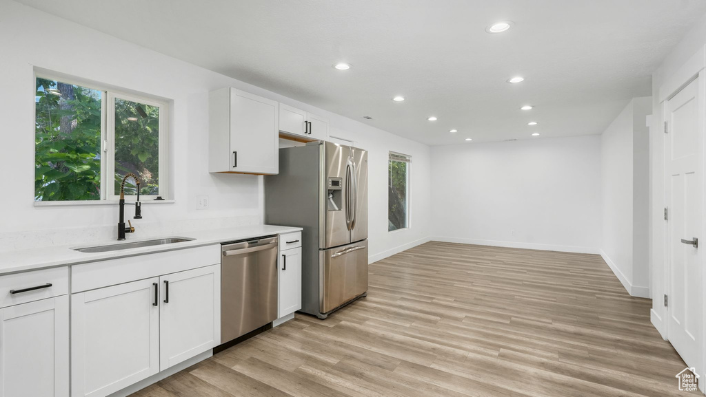 Kitchen with appliances with stainless steel finishes, recessed lighting, plenty of natural light, white cabinetry, and light wood-style flooring