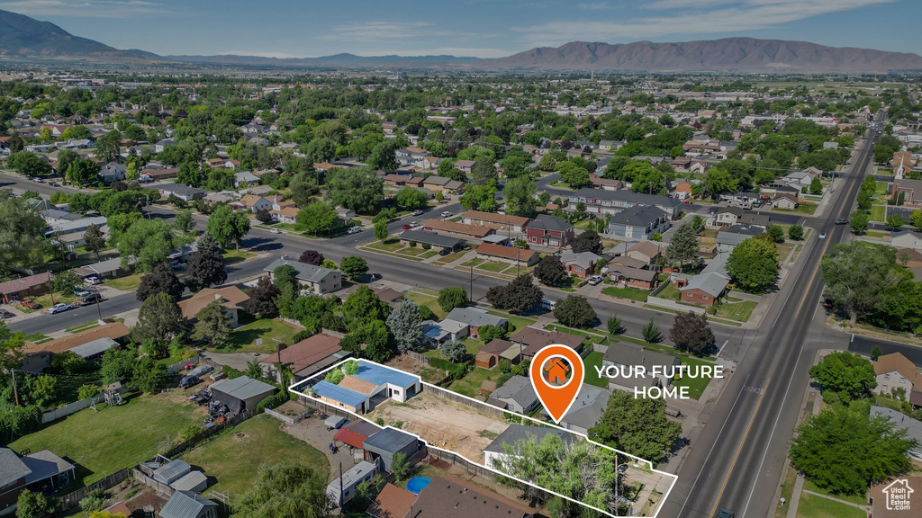Aerial view of property and surrounding area with property boundaries highlighted, a mountainous background, and nearby suburban area