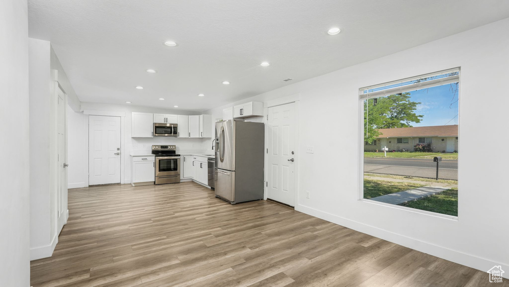 Kitchen featuring stainless steel appliances, recessed lighting, white cabinets, light wood-type flooring, and light countertops