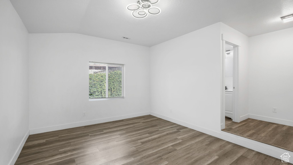 Spare room with wood finished floors and lofted ceiling