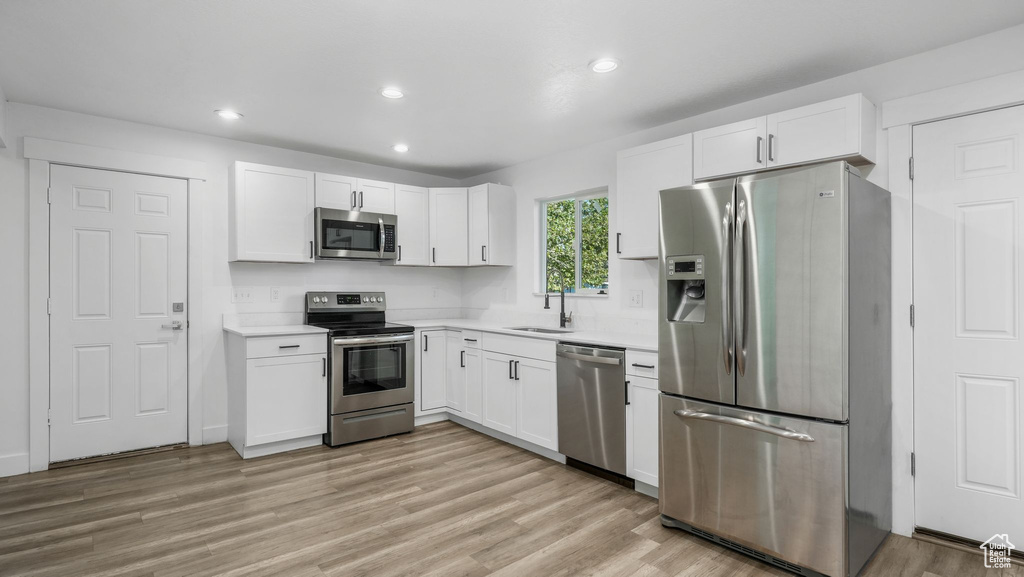 Kitchen with stainless steel appliances, white cabinetry, light countertops, and recessed lighting