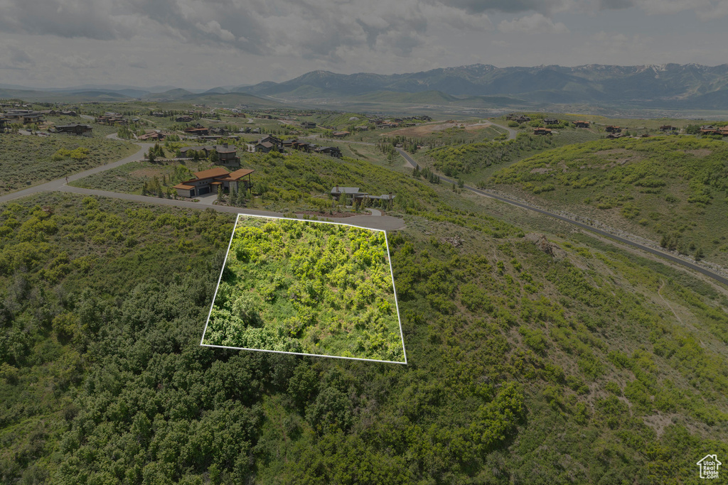 Aerial view of property and surrounding area featuring property boundaries highlighted and a mountainous background